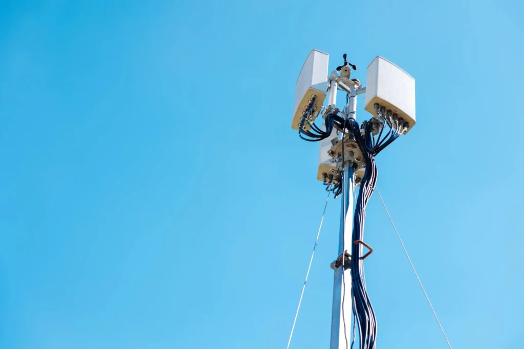 Communications antenna and radio transmission equipment mounted on a mast against a clear blue sky.