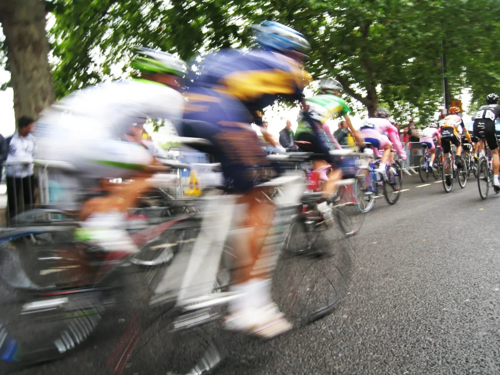 Professional cycling race passing through a controlled event route with spectators and security barriers.