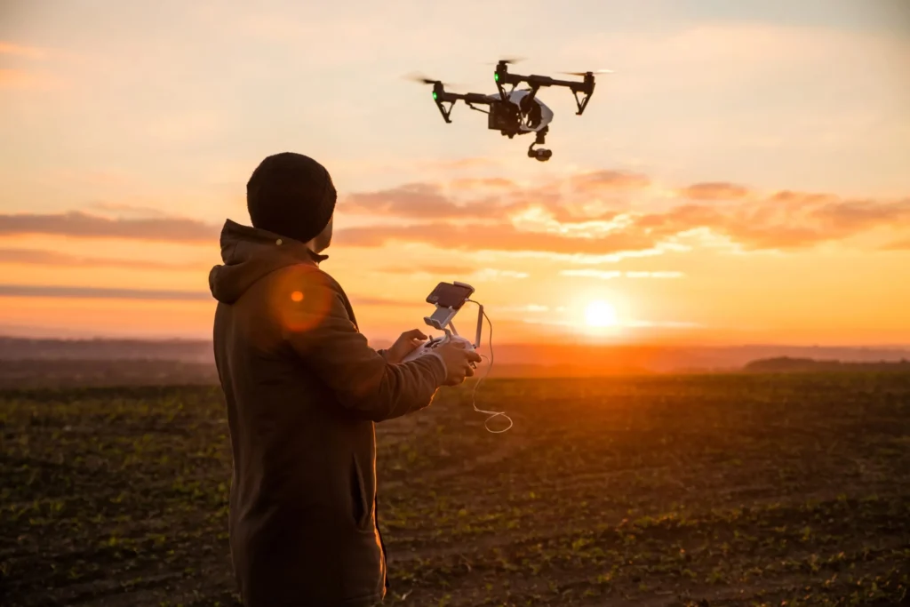 Drone operator controlling a UAV during an aerial surveillance flight over an outdoor site.