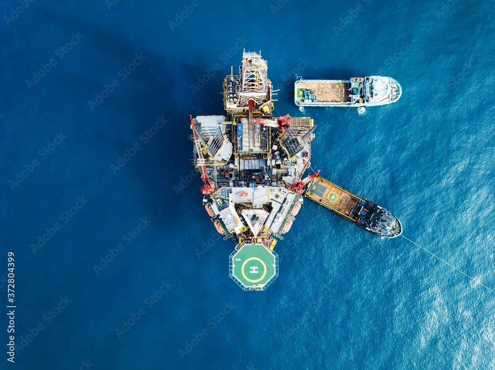 Aerial view of an offshore oil platform with support vessels operating at sea.